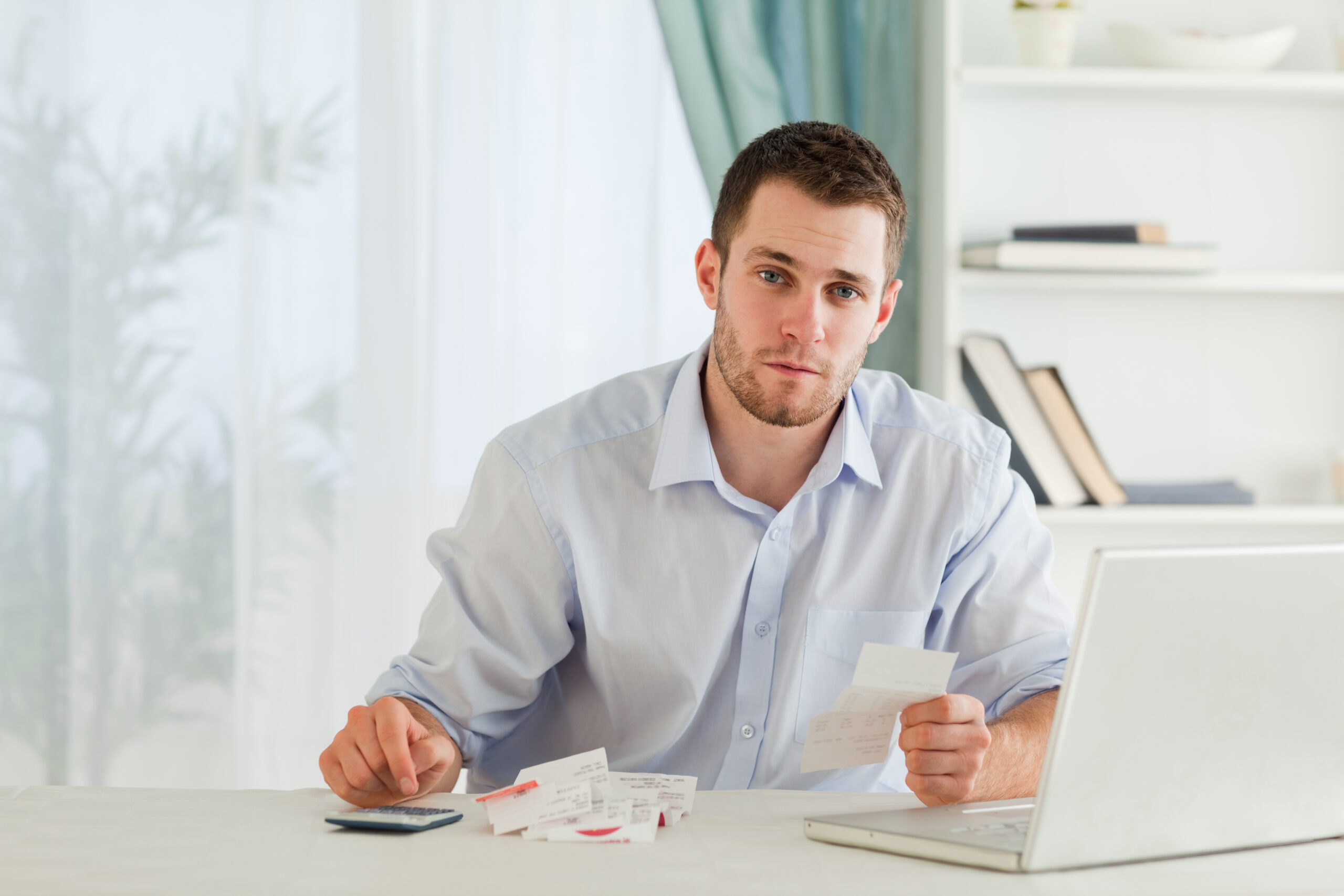 Young businessman checking bills in his homeoffice